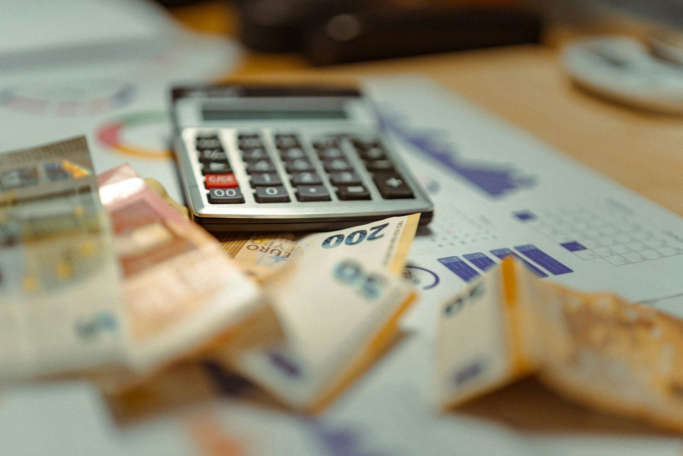 Image shows a desktop with some graphs, a calculator, and paper money